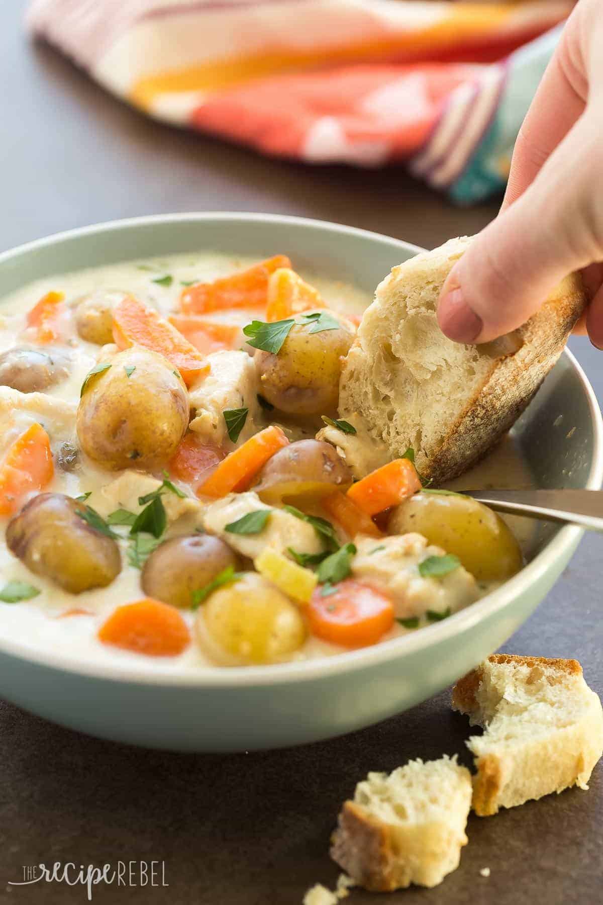 slow cooker garlic parmesan chicken stew in blue bowl with crusty bread dipping