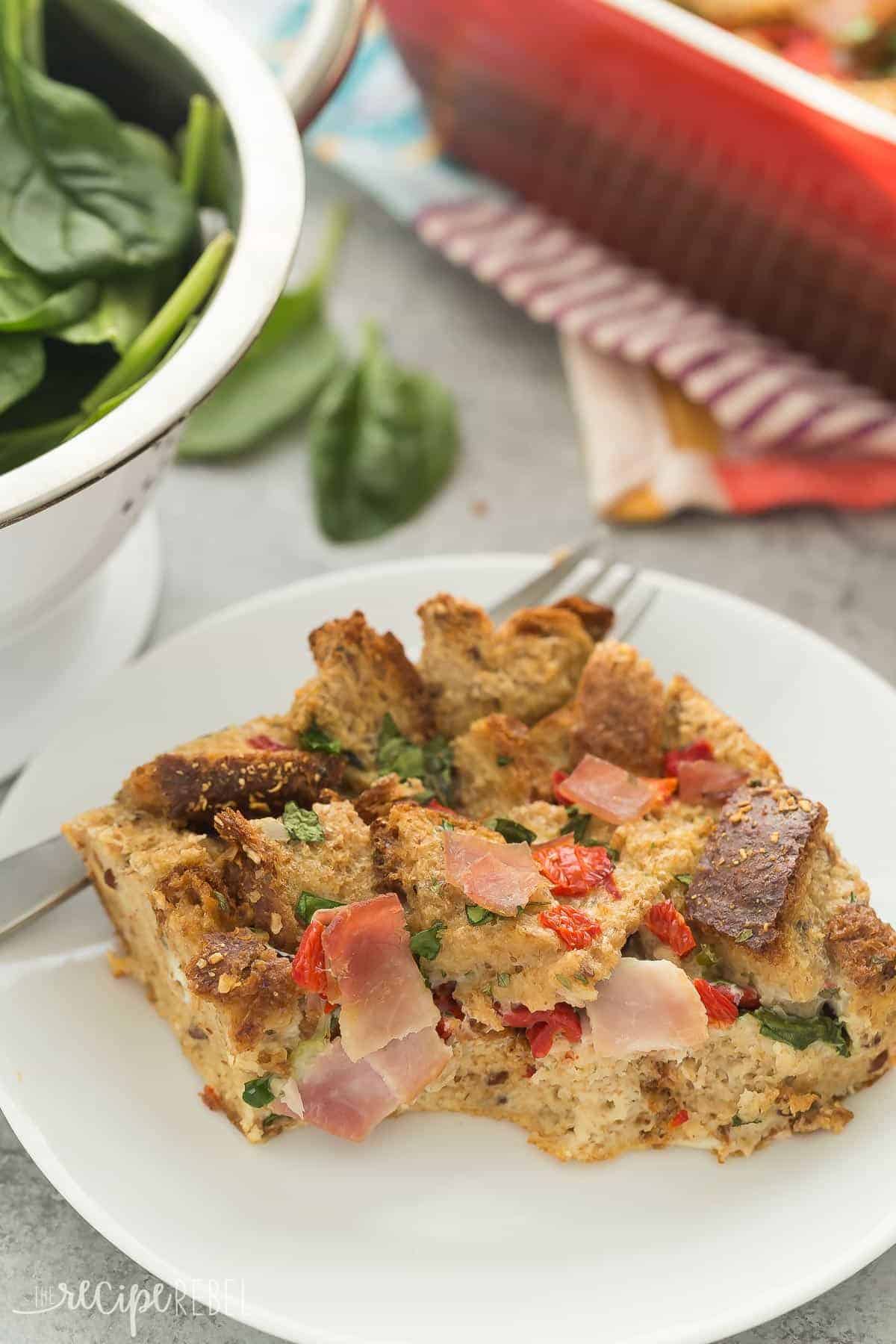 piece of spinach and ham breakfast casserole on white plate with pan in the background