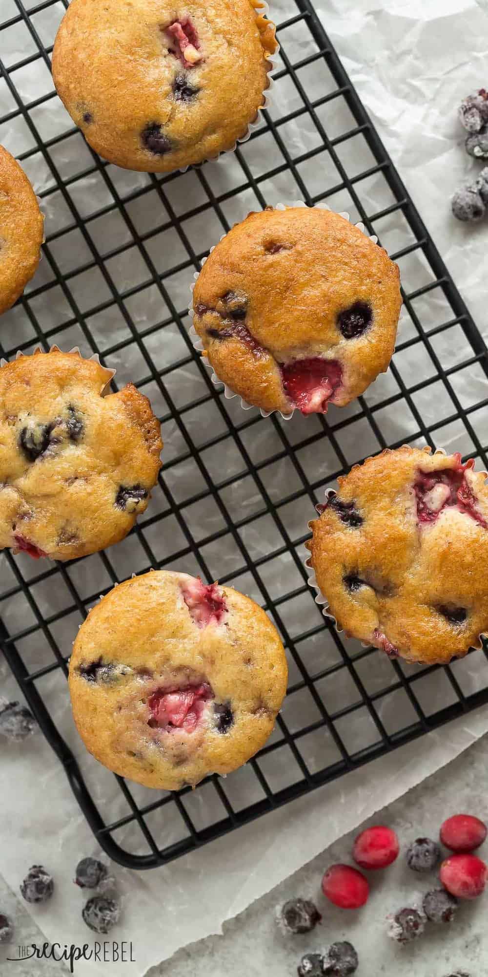 These Fruit Explosion Muffins are loaded with strawberries and blueberries (or any berries you want!) and have a strawberry jam surprise inside! They are made with whole wheat flour and sour cream makes them extra moist. Tall overhead image of fruit explosion muffins on black cooling rack