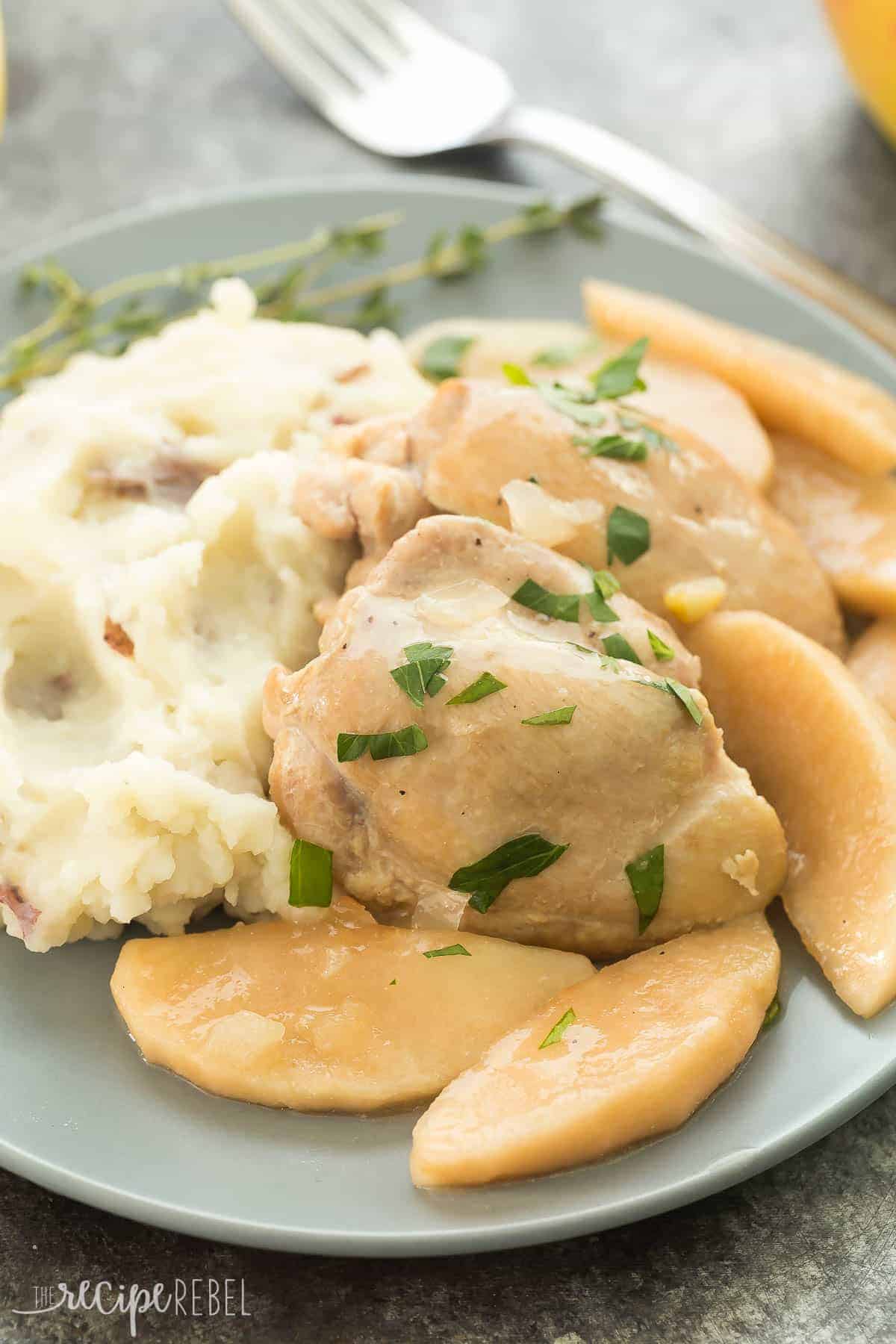 chicken thighs with cooked apples on a bed of mashed potatoes on grey plate