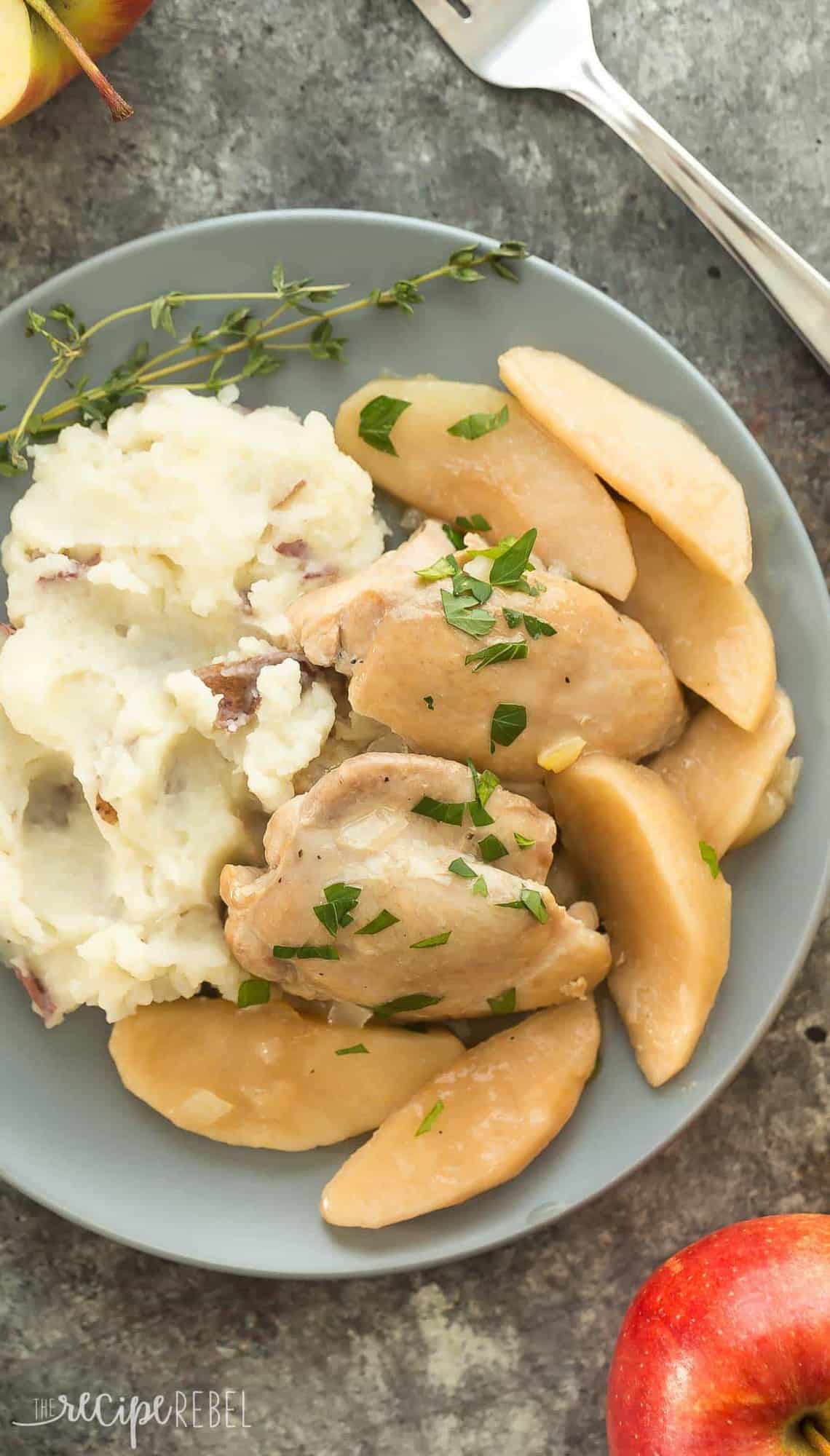 overhead image of chicken thighs apples and mashed potatoes on a grey plate