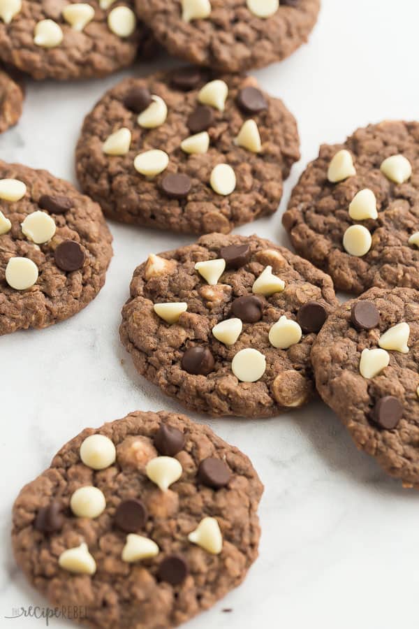 These Double Chocolate Oatmeal Cookies are chewy, chocolatey perfection! They are quick and easy to make and loaded with oats and white chocolate chips. #cookies #chocolate #baking #recipes #dessert chocolate oatmeal cookies on white marble background with white and dark chocolate chips