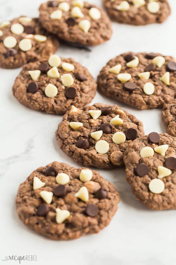 chocolate oatmeal cookies scattered on white marble background with white and dark chocolate chips