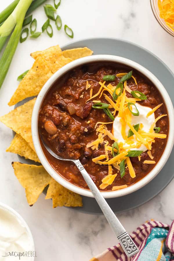 crockpot chili in white bowl overhead with tortilla chips