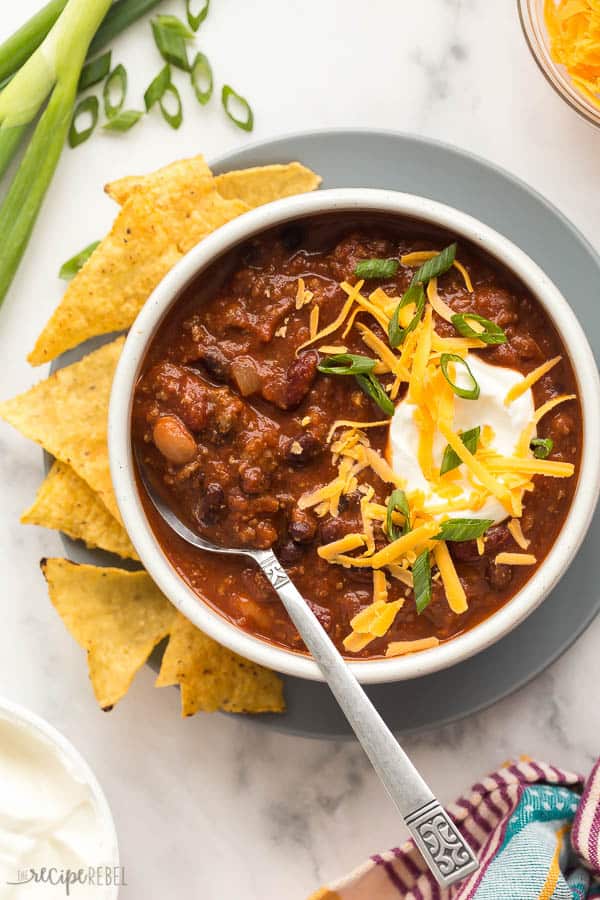 These EASY Crockpot Meals are perfect for those busy weekdays when it's a struggle to get dinner on the table, cozy and comforting for cooler days, or light and fresh for summer days. There's something for everyone! Crockpot pasta, soups, tacos, slow cooker ribs, pork, chicken or beef. TONS of easy crockpot dinners. #crockpot #slowcooker #easyrecipe #recipe #recipes #dinner #cooking crockpot chili in bowl overhead with sour cream cheese and green onions on top
