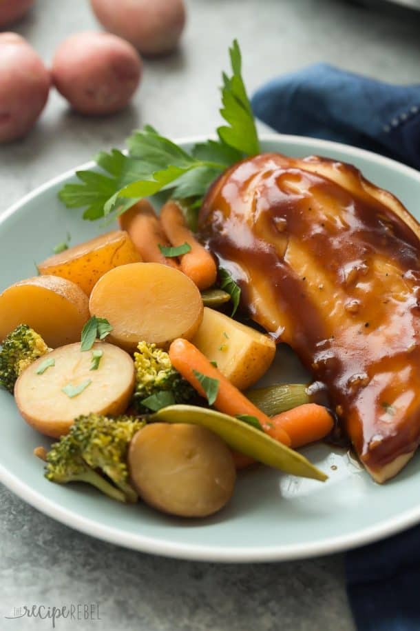 slow cooker honey garlic chicken and vegetables on blue plate with potatoes carrots and broccoli