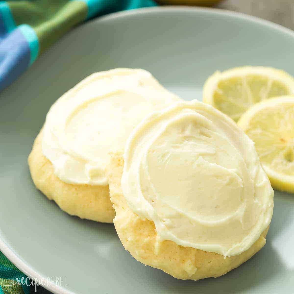 These Lemon Sour Cream Sugar Cookies are soft, moist and loaded with lemon! There's no chilling or rolling -- just stir, drop, bake and frost (if you want to!). Perfect for Easter or Christmas baking. Includes how to recipe video square image of lemon frosted sour cream cookies with lemon slices on blue plate