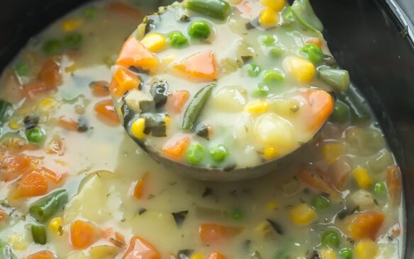 slow cooker creamy vegetable soup being pulled out of crockpot in metal ladle