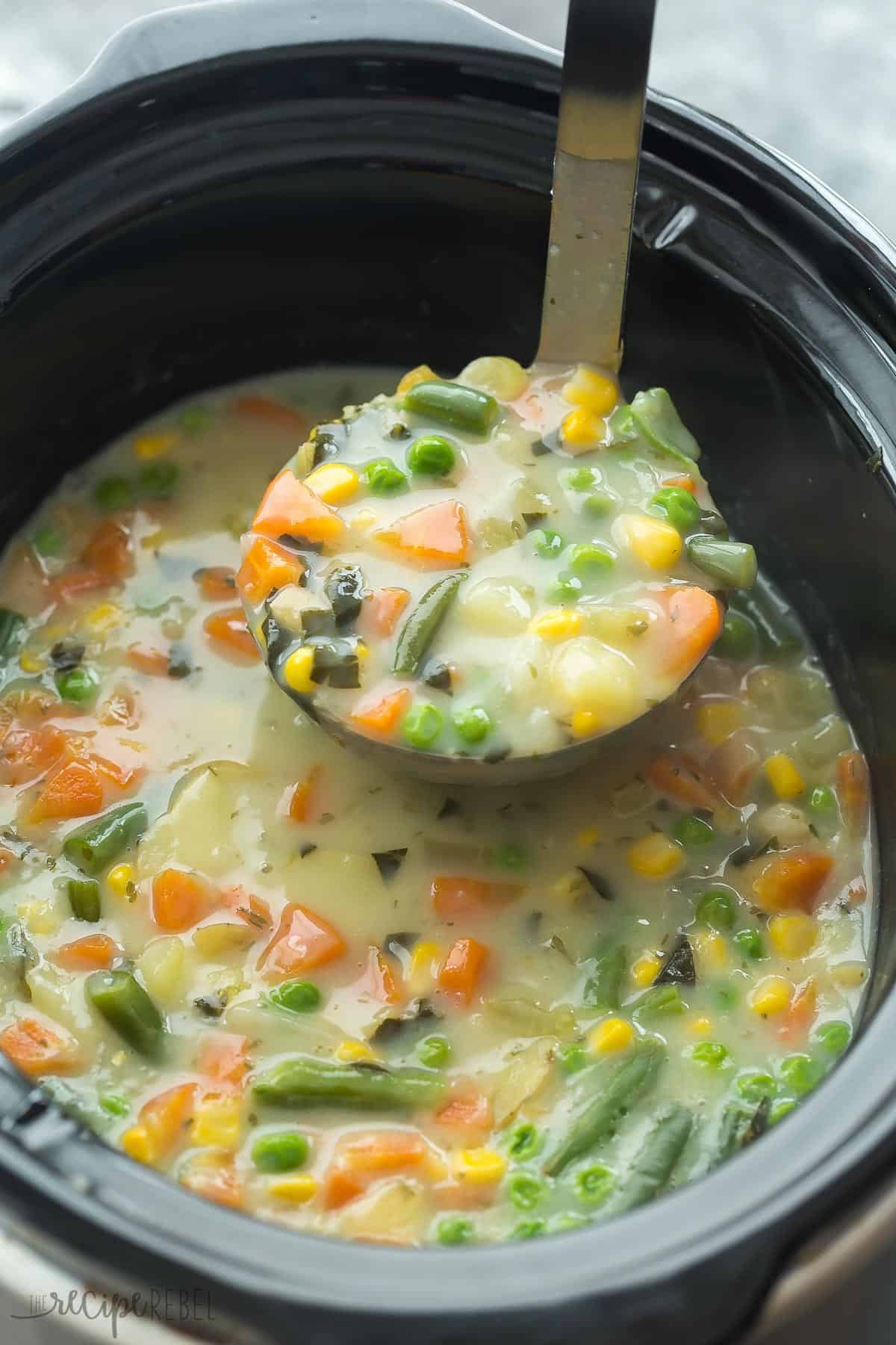 slow cooker creamy vegetable soup being pulled out of crockpot in metal ladle