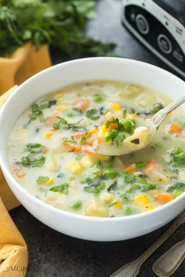 Slow Cooker Creamy Vegetable Soup in white bowl with spoon pulling up some soup