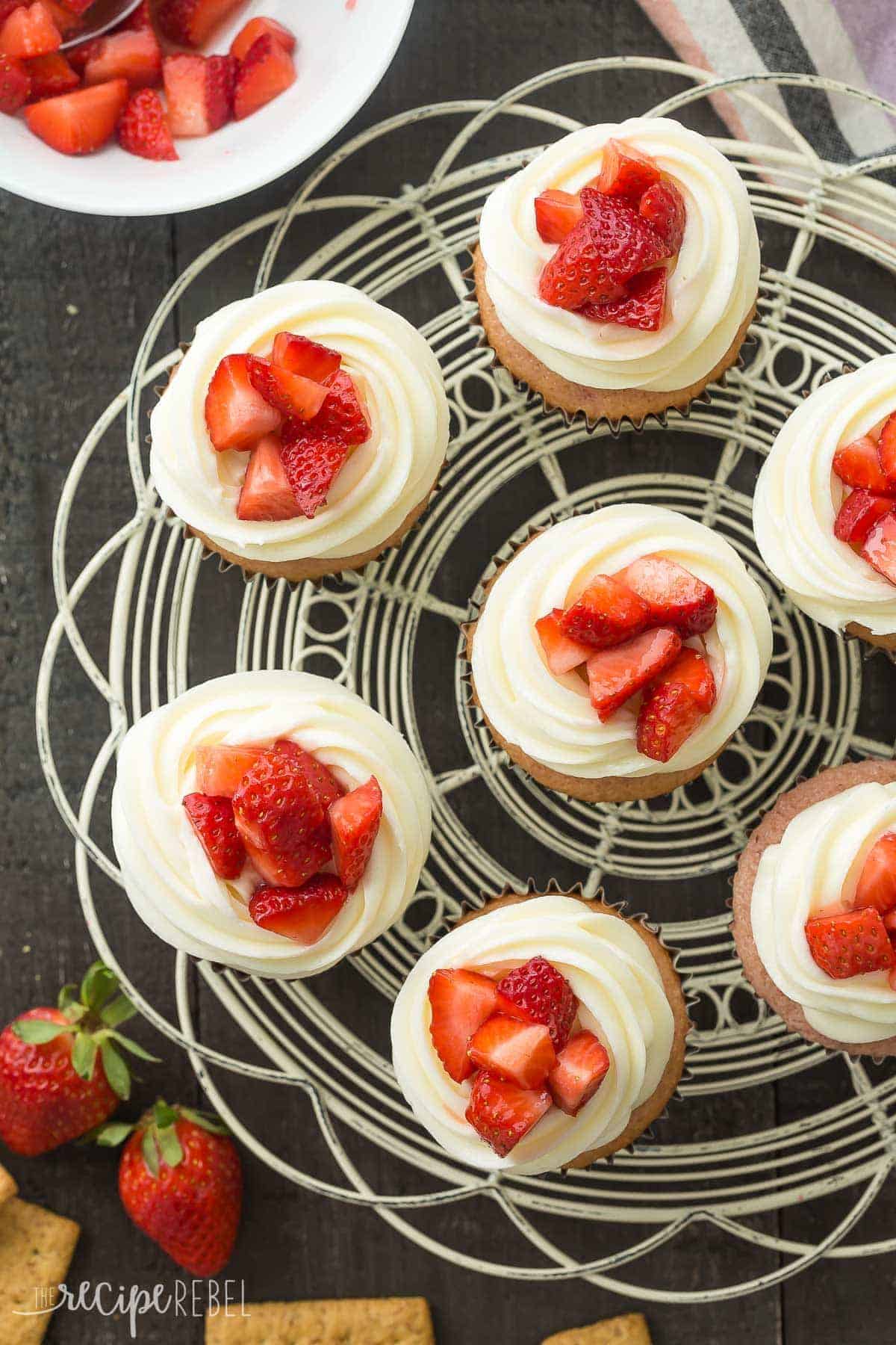 overhead image of a tray of strawberry cheesecake cupcakes with fresh chopped strawberries on top