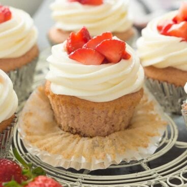 These Strawberry Cheesecake Cupcakes have a graham cracker base topped with a strawberry cake layer, cream cheese frosting and fresh strawberries. Perfect for any birthday, Easter dinner or Spring celebration! Sprinkles bakery recipe. | strawberry recipe | spring | Easter | Christmas | dessert recipe