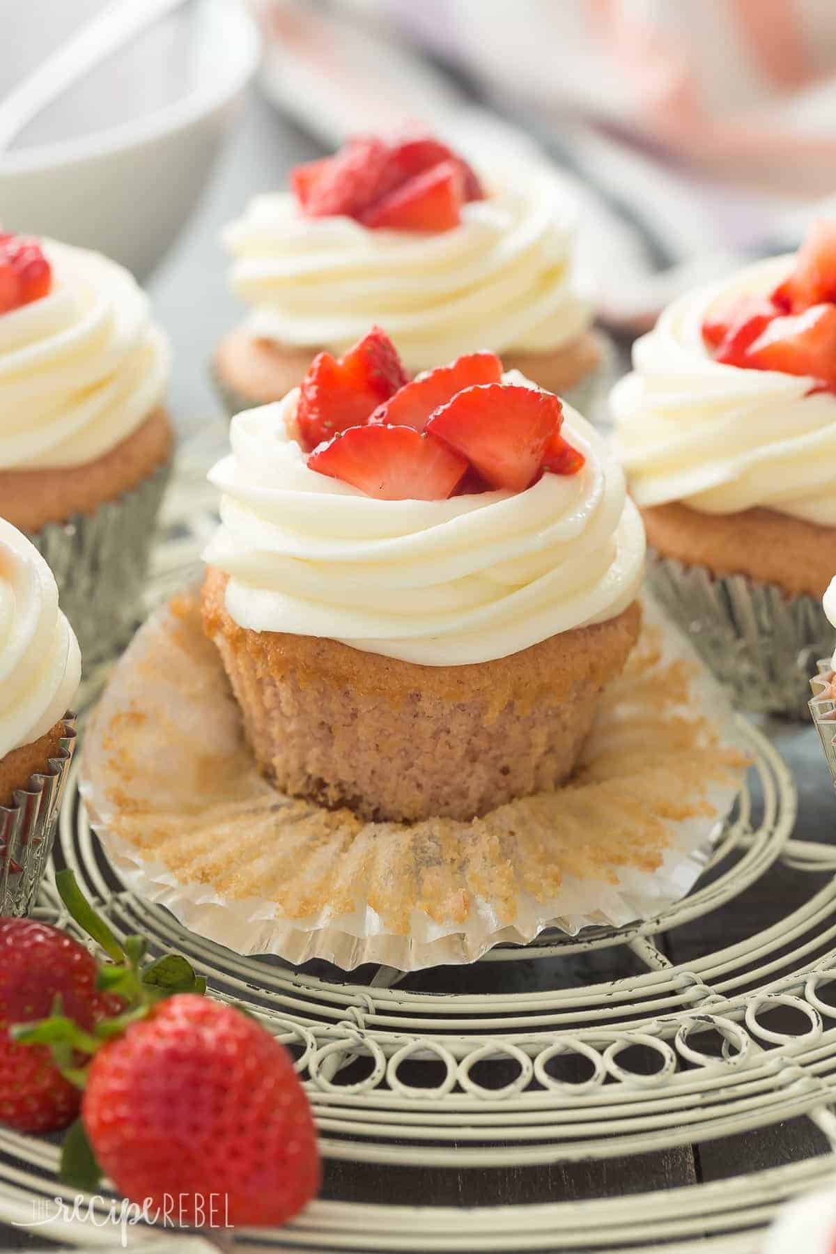 strawberry cheesecake cupcakes up close unwrapped with cupcakes behind