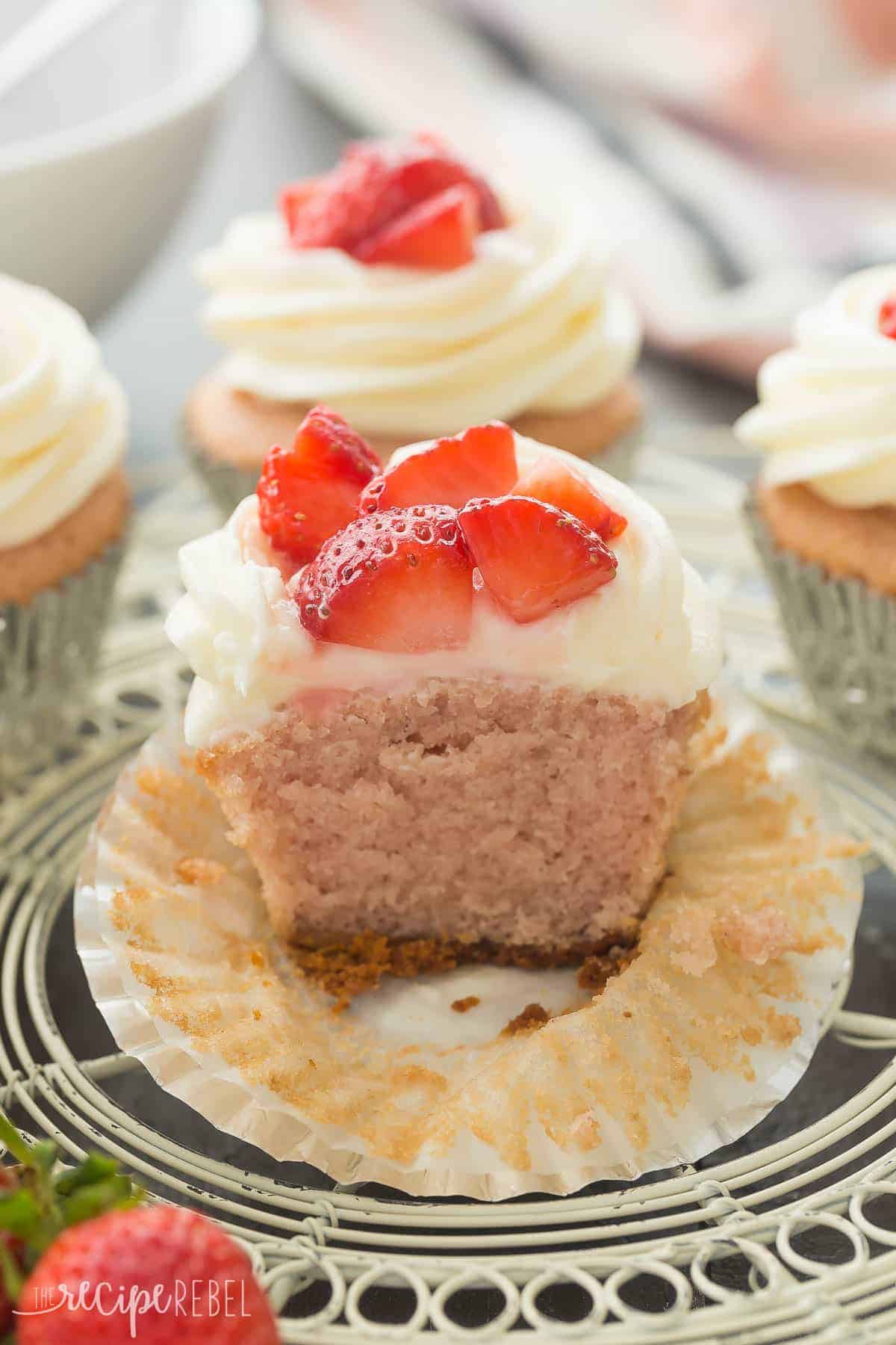 strawberry cheesecake cupcake cut in half to reveal pink cupcake and graham cracker crust on bottom