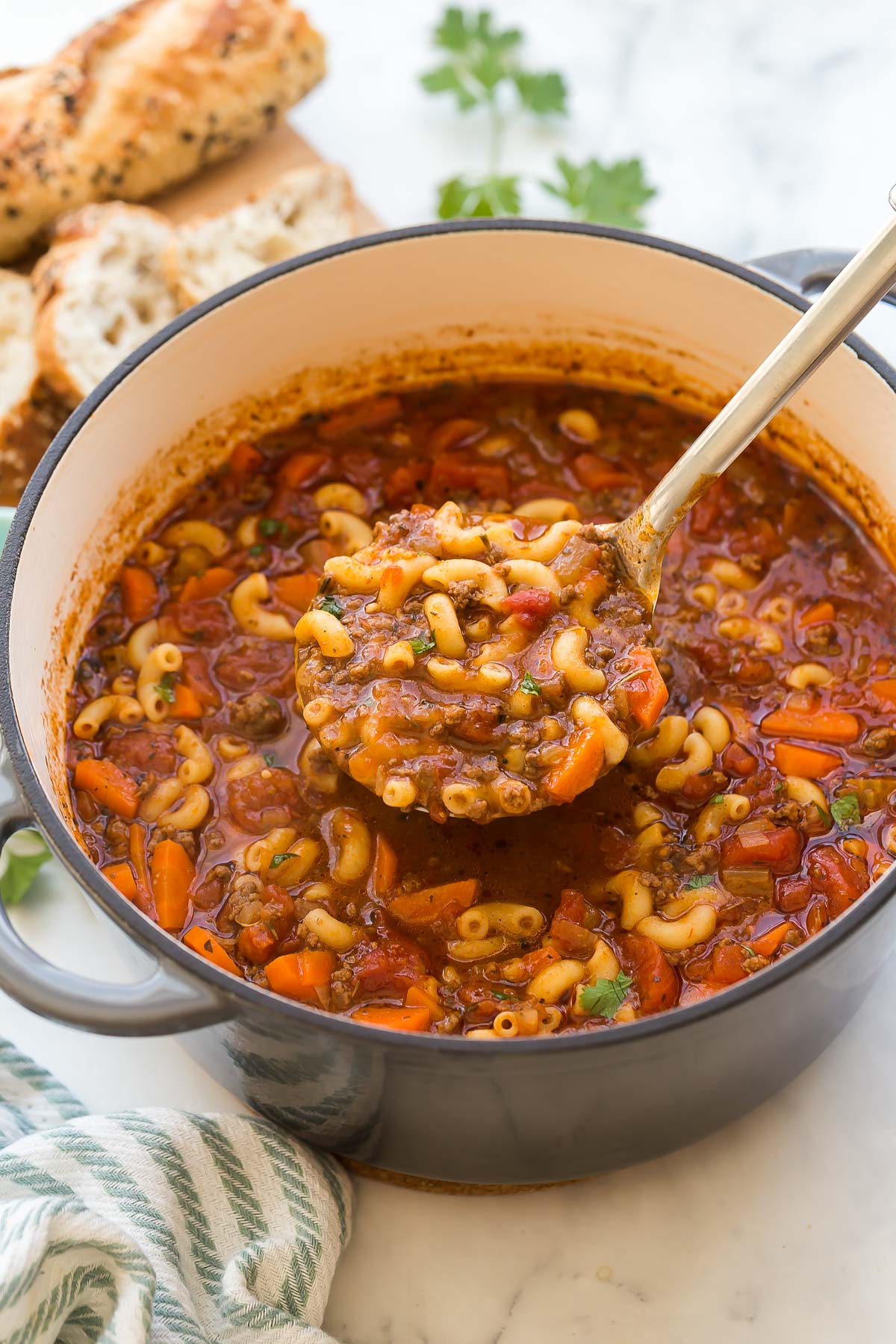 metal ladle scooping beef and tomato macaroni soup