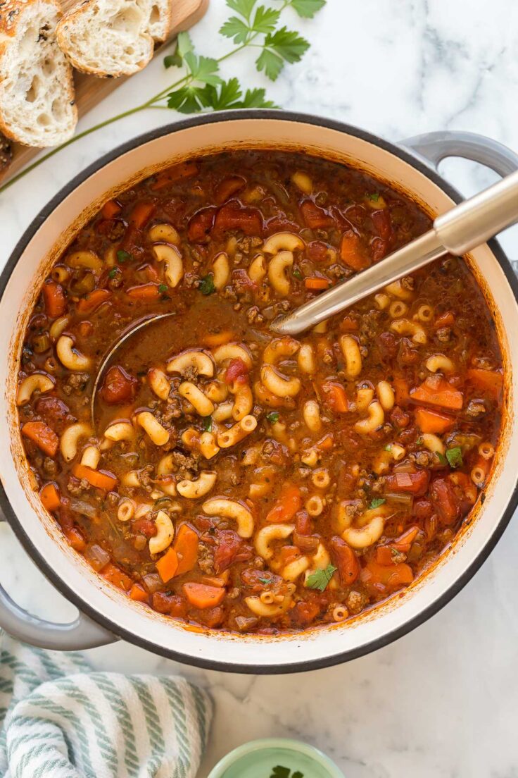 This Tomato Macaroni Soup is a hearty and healthy one-pot meal that's ready in under 30 minutes. It's packed with tender ground beef, whole wheat macaroni pasta, veggies, tomato sauce, and more! #soup #recipes #dinner | easy dinner ideas | healthy soup recipes | ground beef recipes | easy soup recipes overhead image of macaroni soup with ladle stuck in