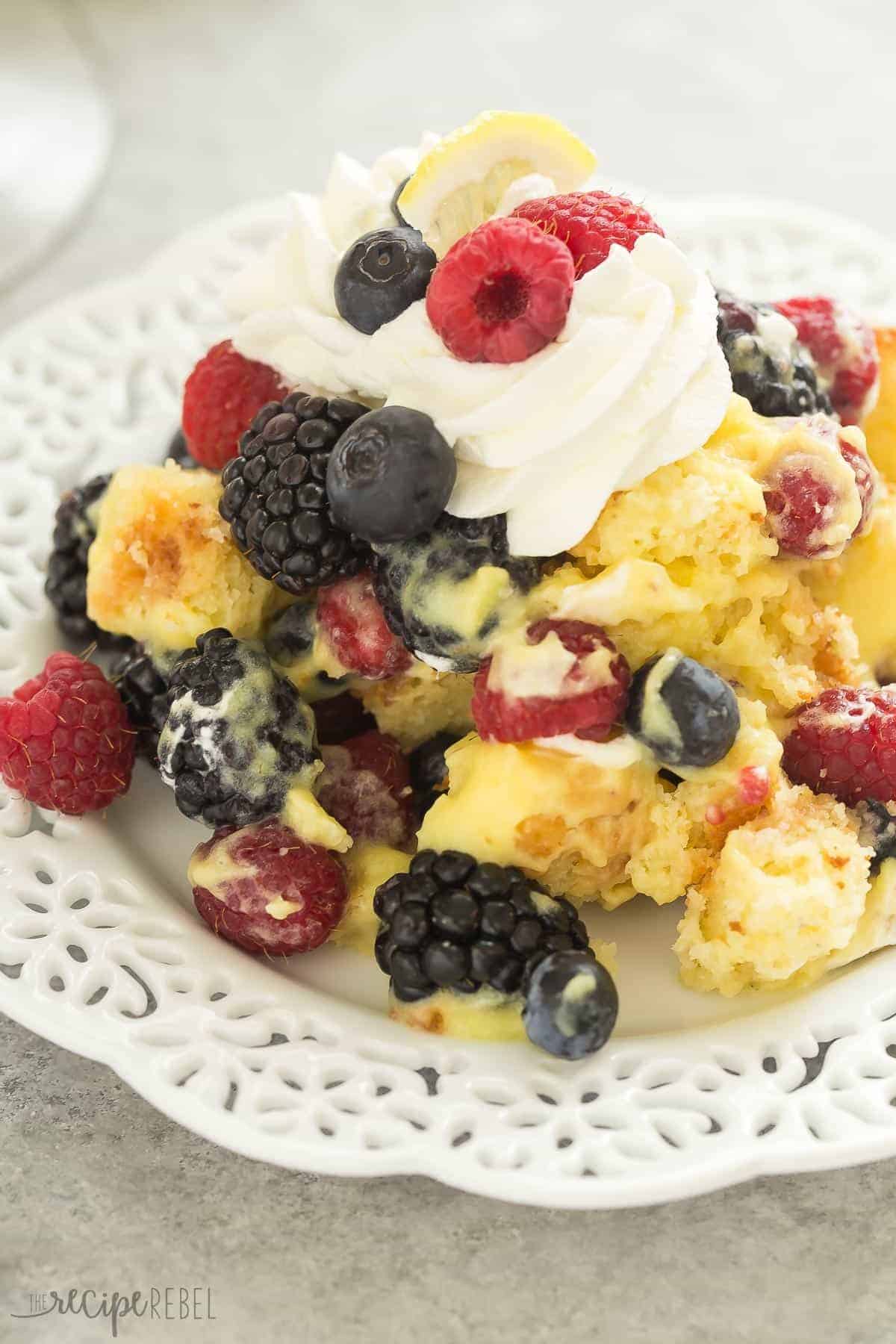 lemon berry trifle on white plate topped with whipped cream and fresh berries