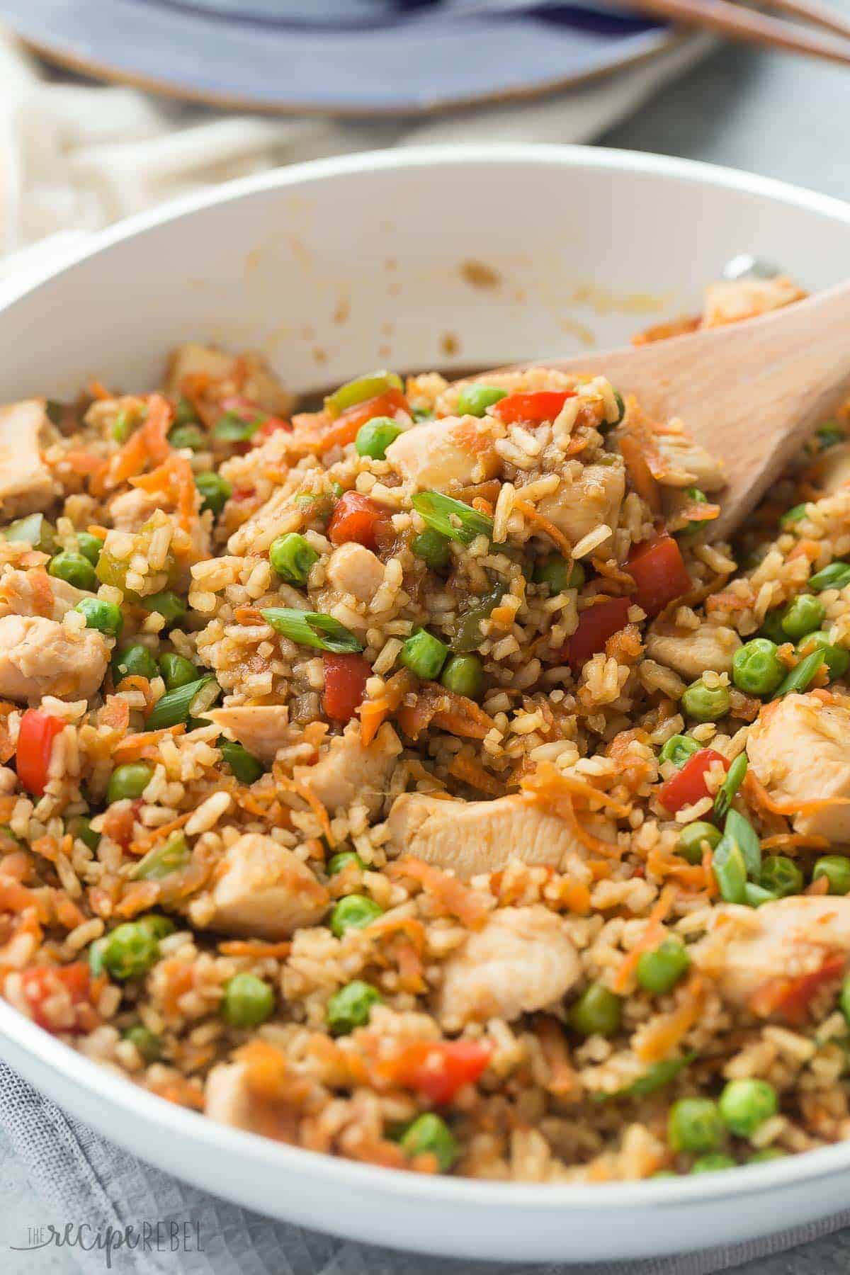 one pot teriyaki chicken and rice in white skillet with wooden spoon scooping up some rice