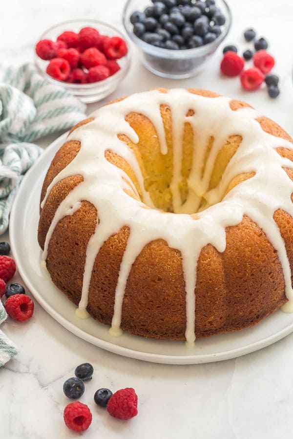 whole glazed lemon bundt cake with blueberries and raspberries in background