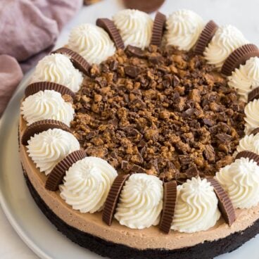 whole peanut butter cup cheesecake with whipped cream and chopped reeses