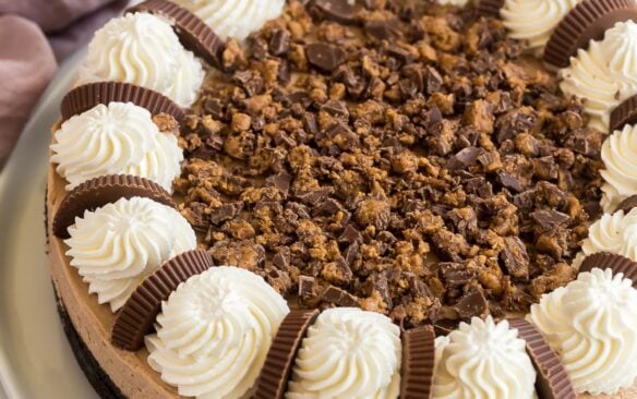 whole peanut butter cup cheesecake with whipped cream and chopped reeses