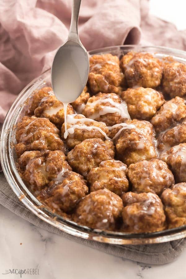 cinnamon roll bites in pan being drizzled with glaze