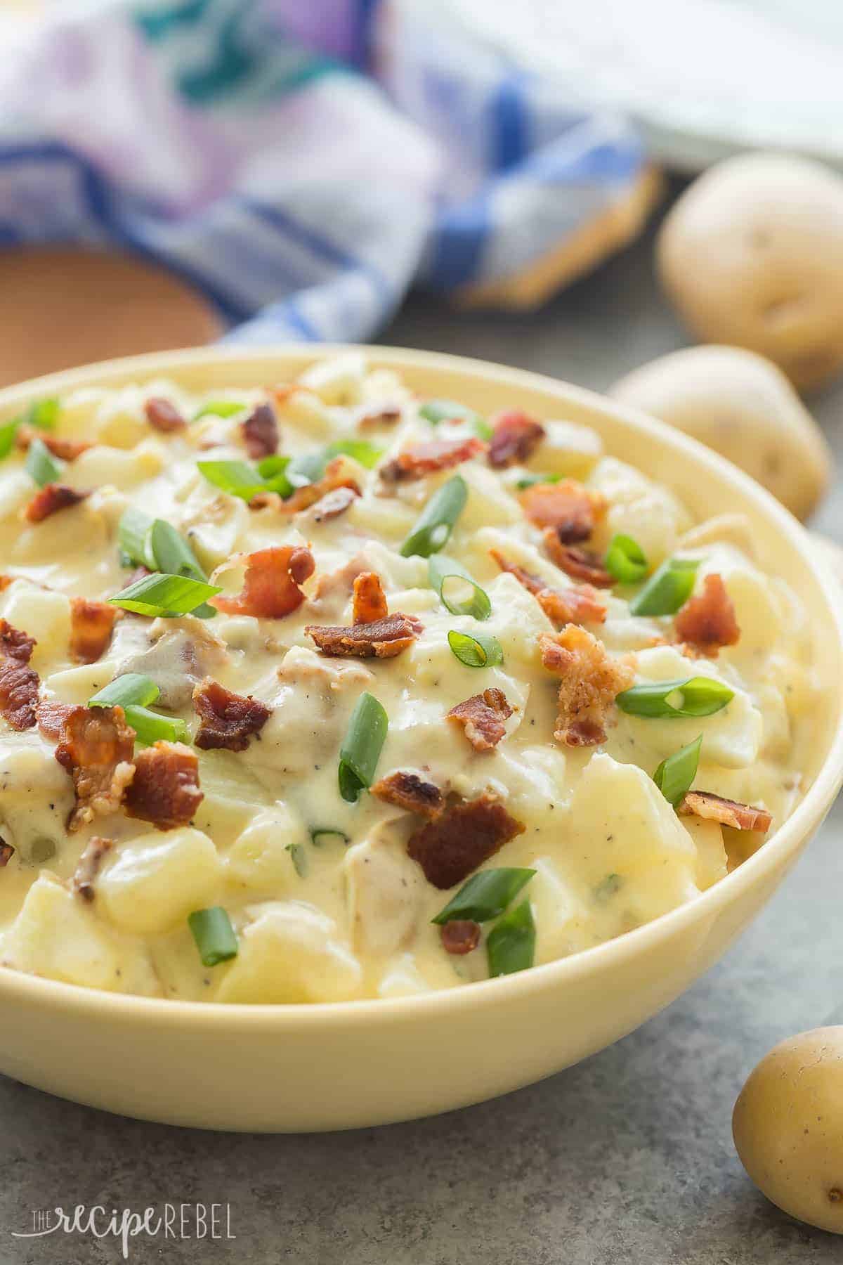 classic potato salad with bacon in yellow bowl with little potatoes all around