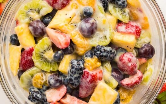 overhead image of creamy fruit salad in glass bowl