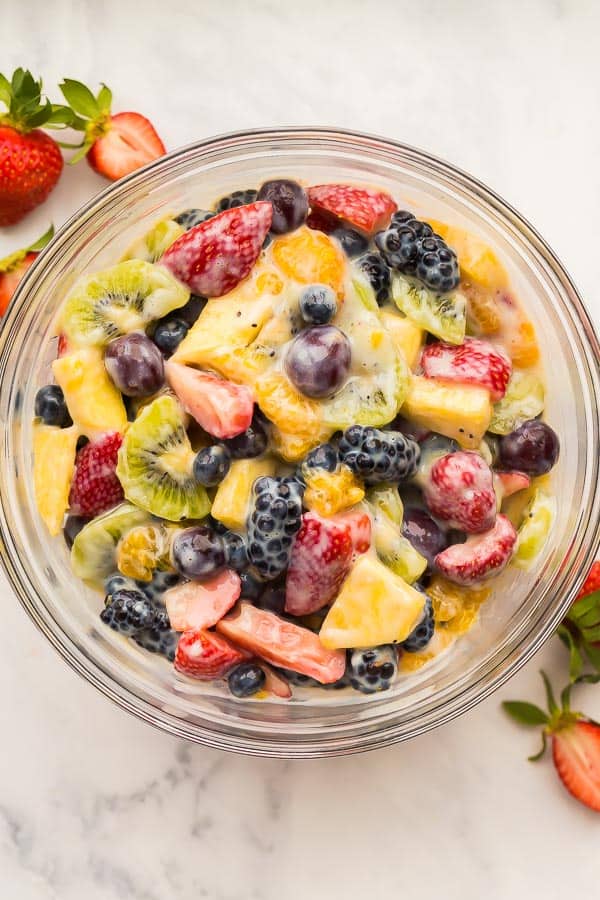 overhead image of creamy fruit salad in glass bowl