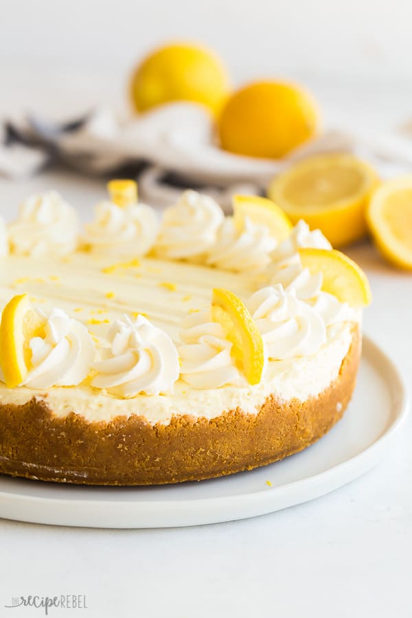 no bake lemon cheesecake whole with whipped cream swirls and lemon slices