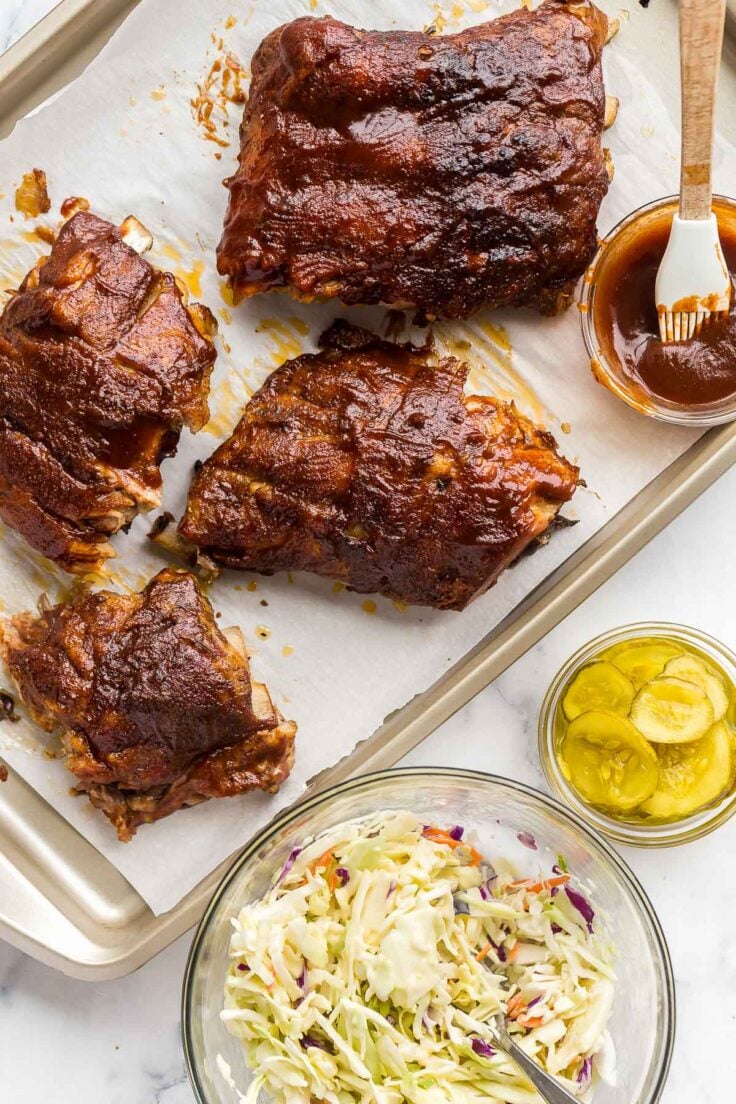 overhead image of slow cooker ribs with coleslaw and pickles