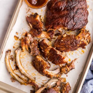 overhead image of meat falling off of bones of slow cooker ribs on sheet pan