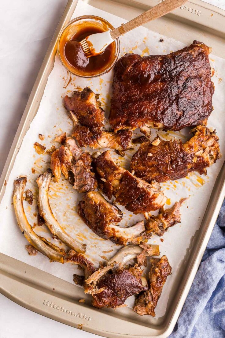 overhead image of meat falling off of bones of slow cooker ribs on sheet pan