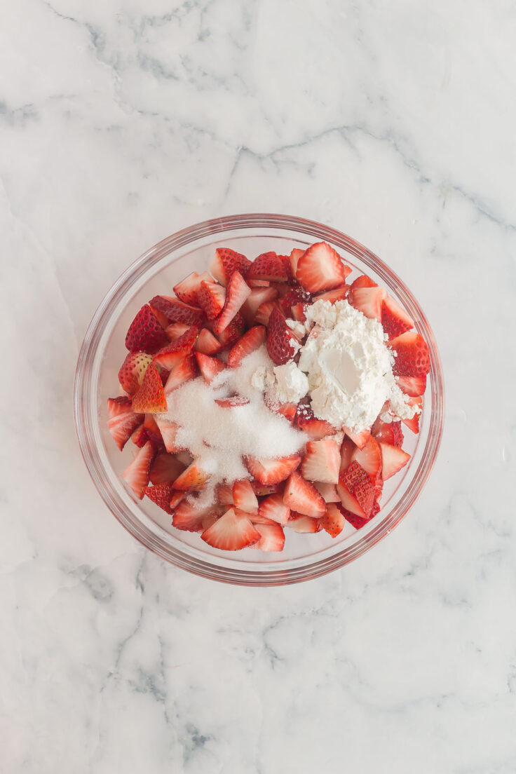 overhead image of strawberries sugar and corn starch in a bowl