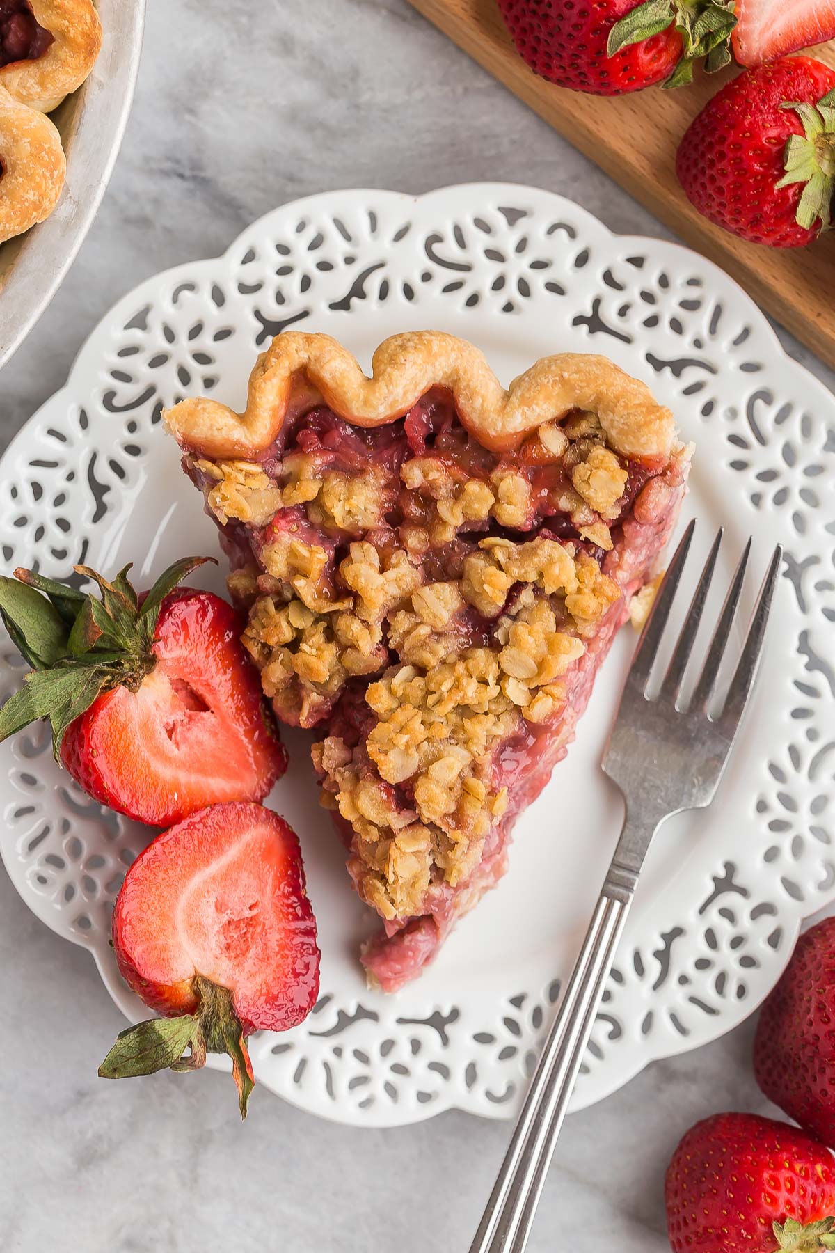 This Streusel-Topped Fresh Strawberry Pie Recipe is loaded with fresh strawberries (you can use any berries!) and topped with a crunchy brown sugar streusel. The best way to use your summer berries! #pie #dessert | strawberry recipes slice of streusel topped fresh strawberry pie in white plate