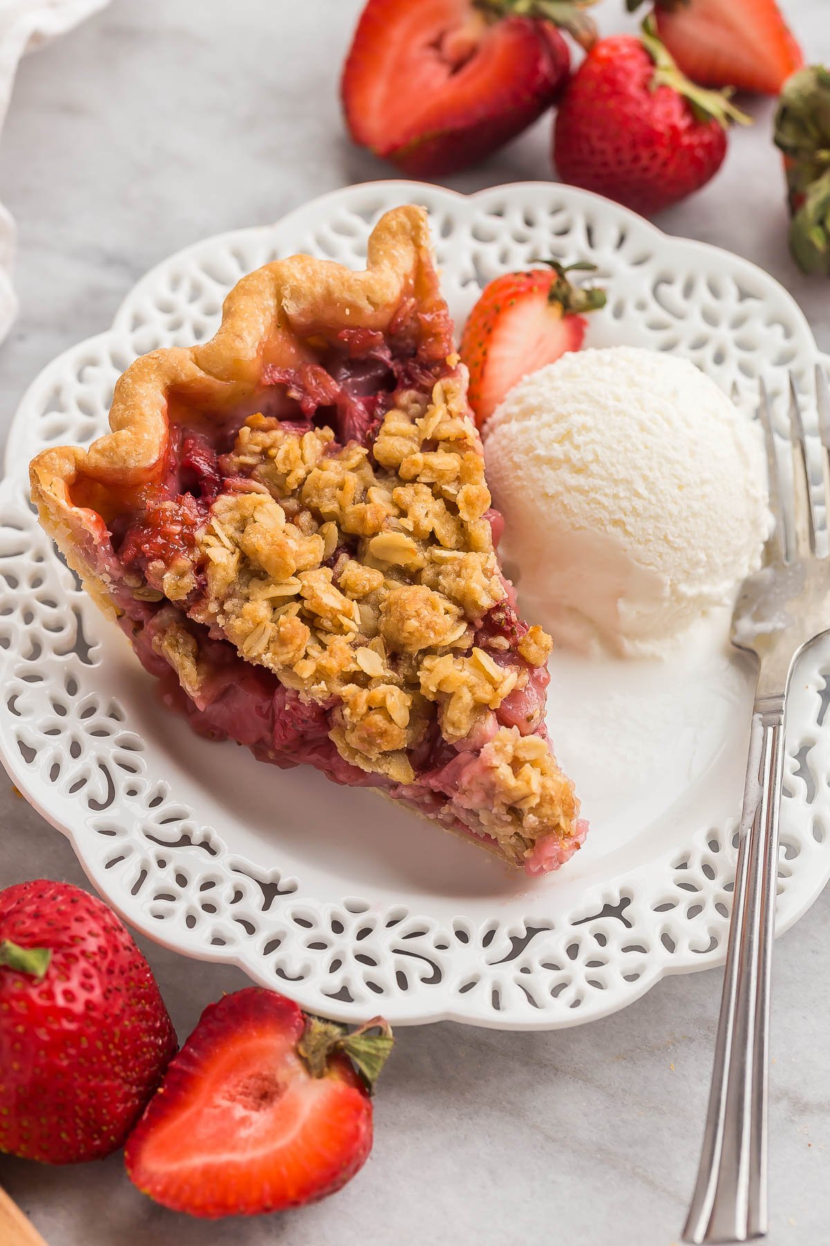 This Streusel-Topped Fresh Strawberry Pie Recipe is loaded with fresh strawberries (you can use any berries!) and topped with a crunchy brown sugar streusel. The best way to use your summer berries! #pie #dessert | strawberry recipes slice of strawberry pie on white plate with ice cream