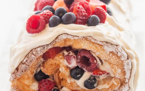 square image of angel food roll cake with fresh berries.