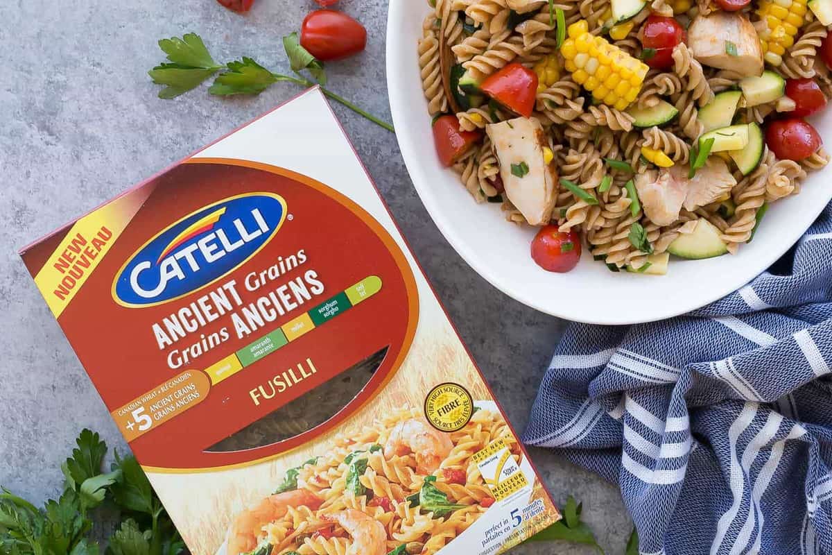 bbq chicken pasta salad overhead in white bowl with catelli box of ancient grains fusili