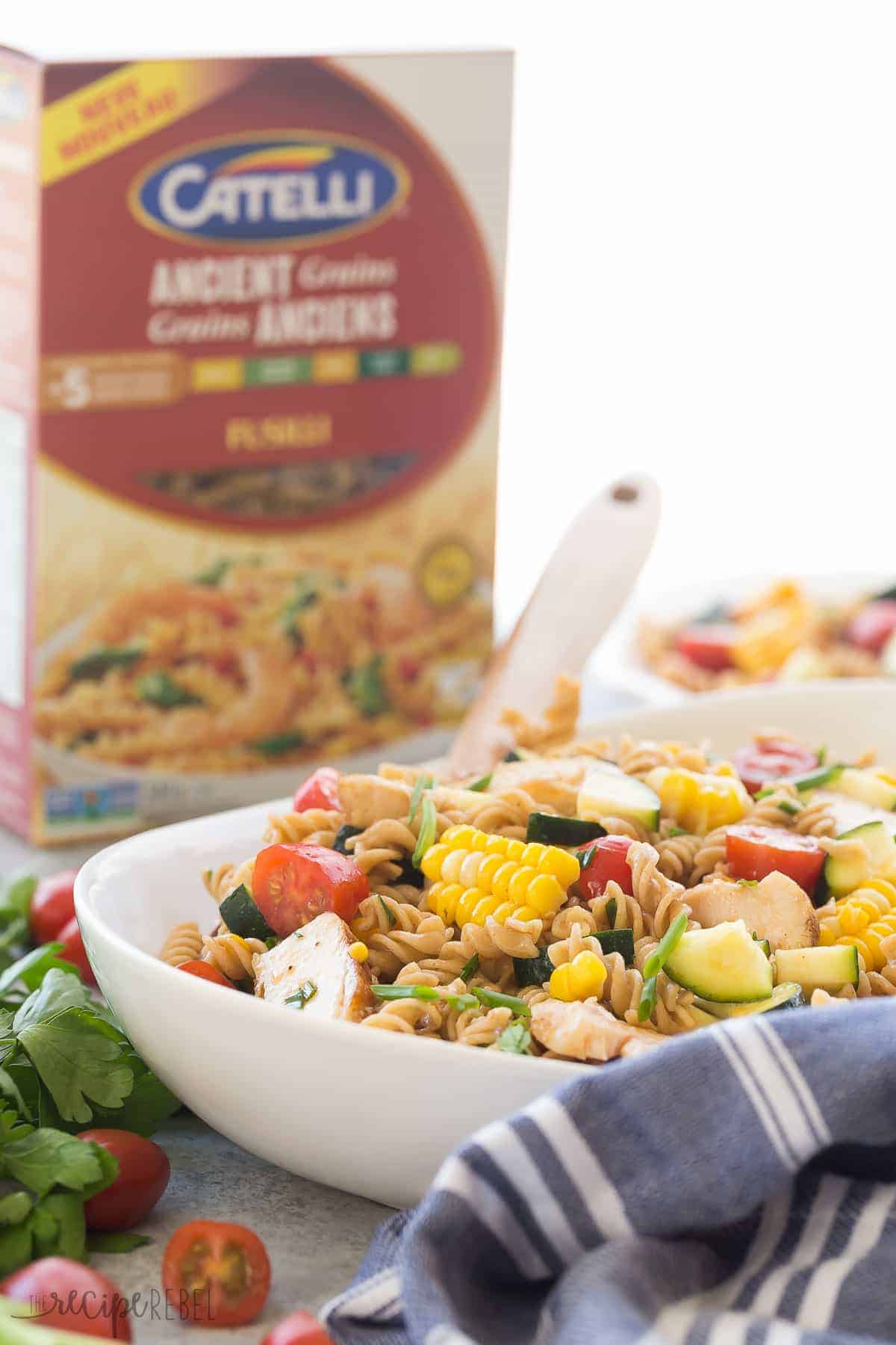 bbq chicken pasta salad in white bowl with catelli ancient grains fusili in the background
