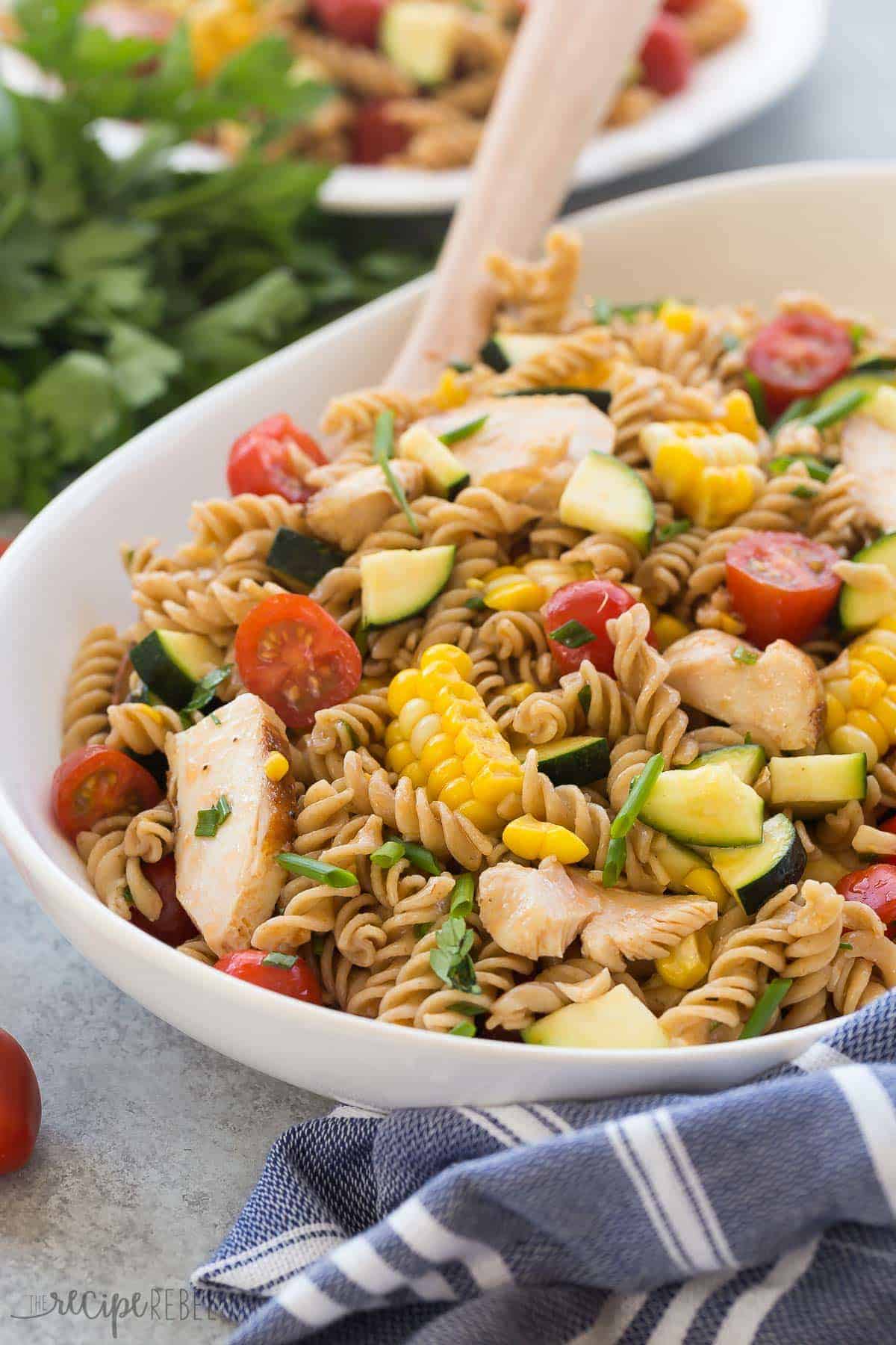 bbq chicken pasta salad in white bowl with wooden spoon stuck in