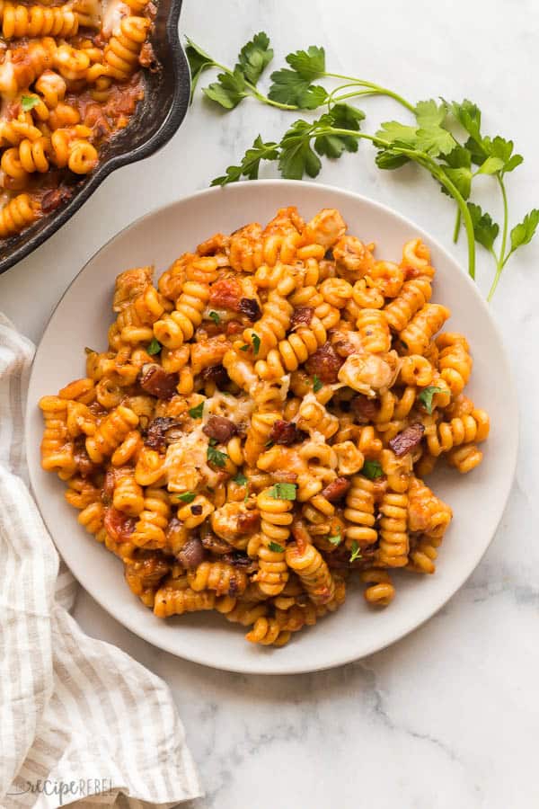 overhead barbecue chicken pasta on white plate with pan on the side