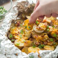 These Cheesy Grilled Potatoes with Bacon are an EASY foil pack side dish or appetizer for summer! Make it a full meal deal by adding extra veggies or chicken. Includes step by step recipe video.