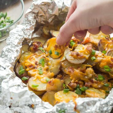 These Cheesy Grilled Potatoes with Bacon are an EASY foil pack side dish or appetizer for summer! Make it a full meal deal by adding extra veggies or chicken. Includes step by step recipe video.