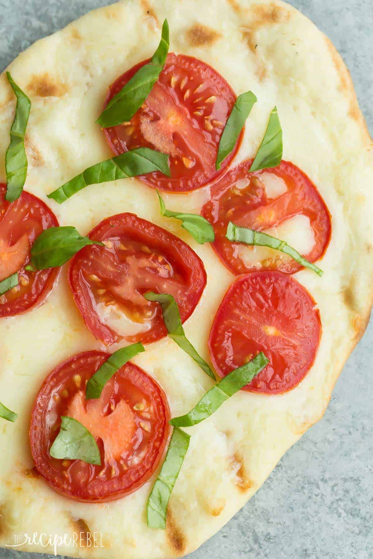 fresh tomato basil grilled pizza with tomato slices and mozzarella on grey background