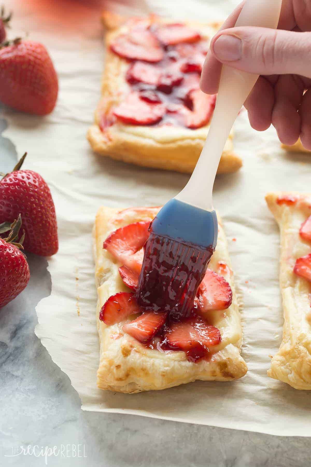 pastry brush brushing strawberry glaze on strawberry cream cheese danish