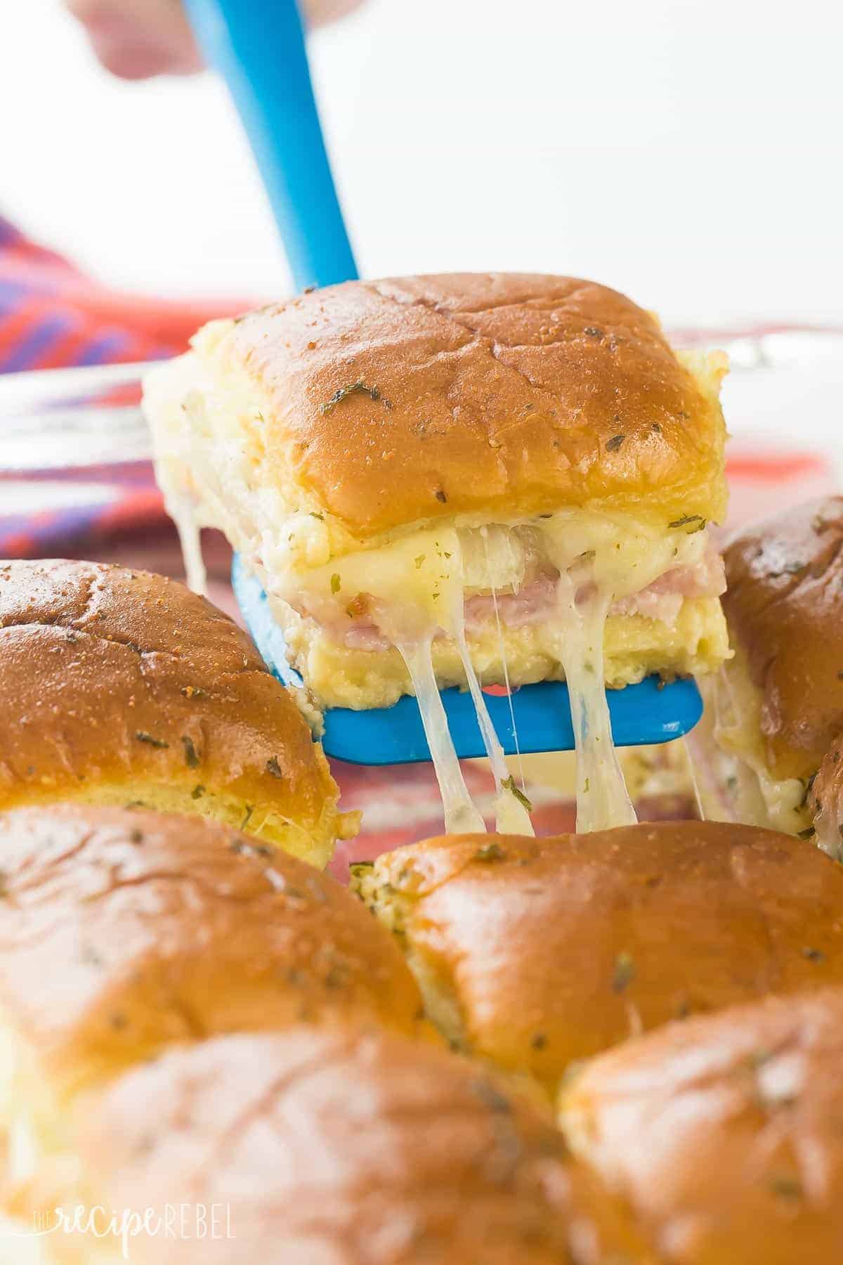 ham and pineapple slider being pulled out of pan on blue spatula