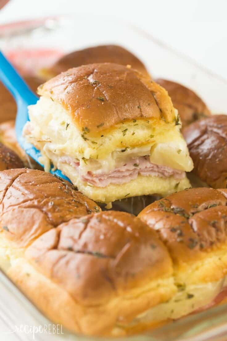 ham and pineapple slider being lifted out of pan on blue spatula