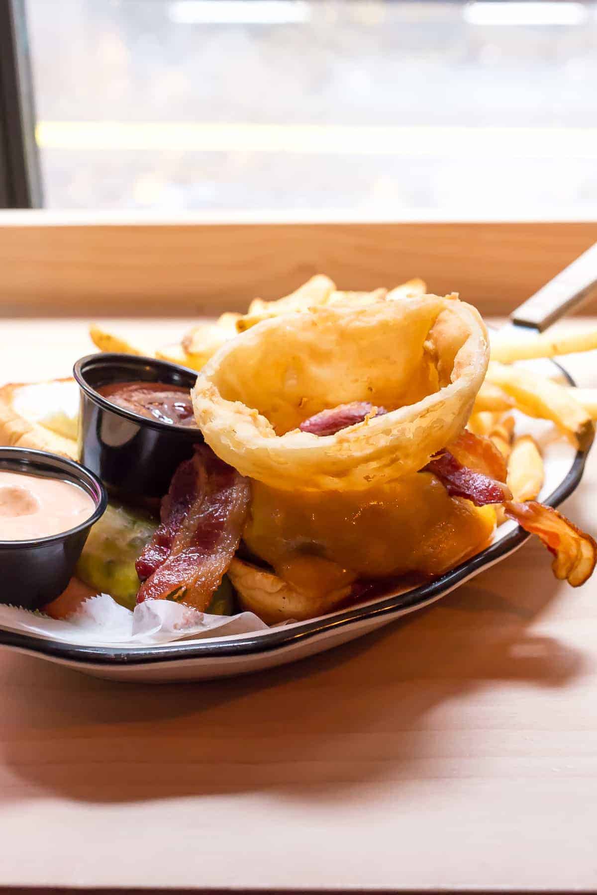 black tap burger with onion ring and bacon in basket
