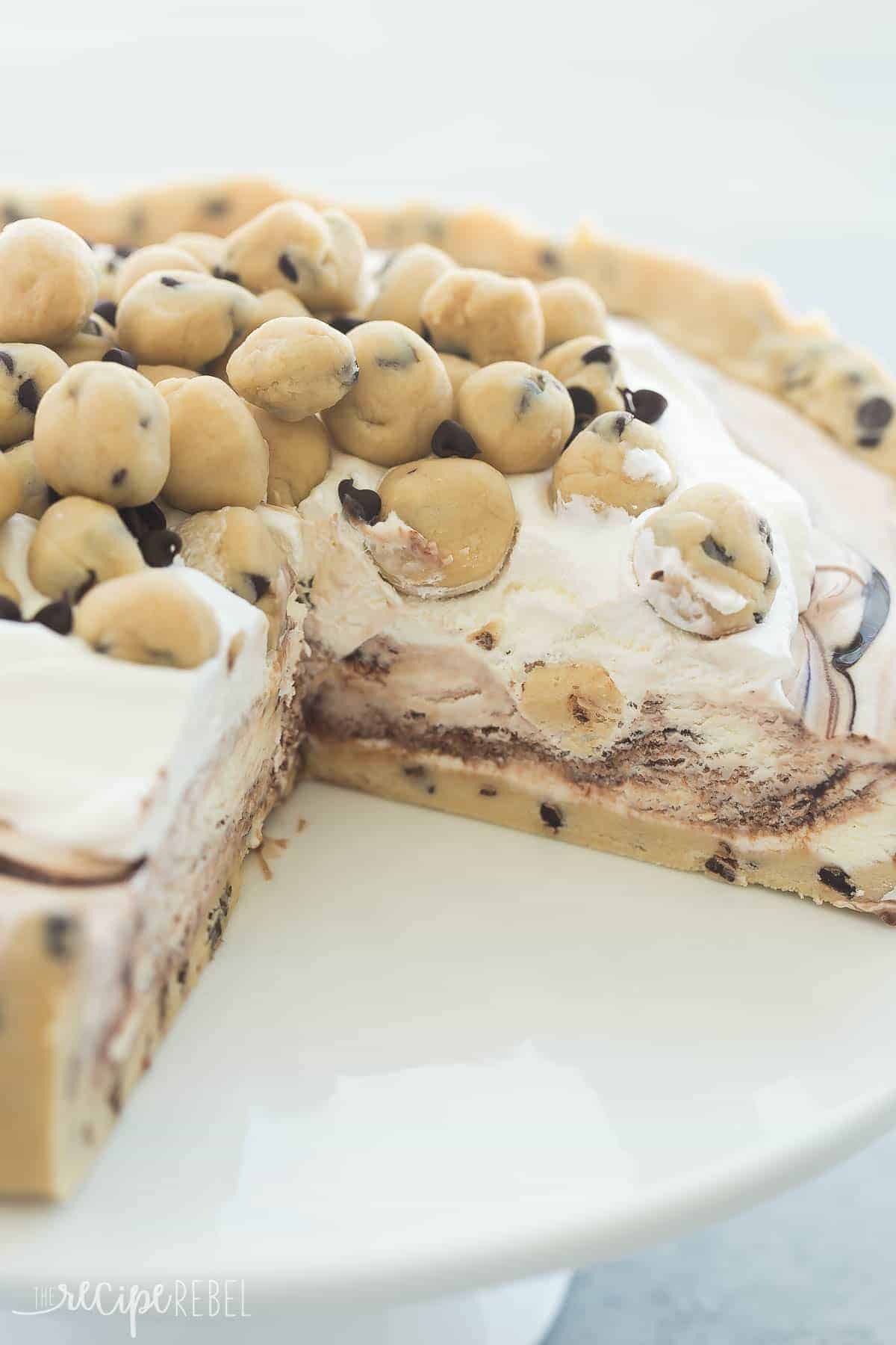 whole cookie dough ice cream cake with slice missing on white cake plate