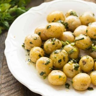 No mayo potato salad with little potatoes whole in garlic herb dressing on white plate.